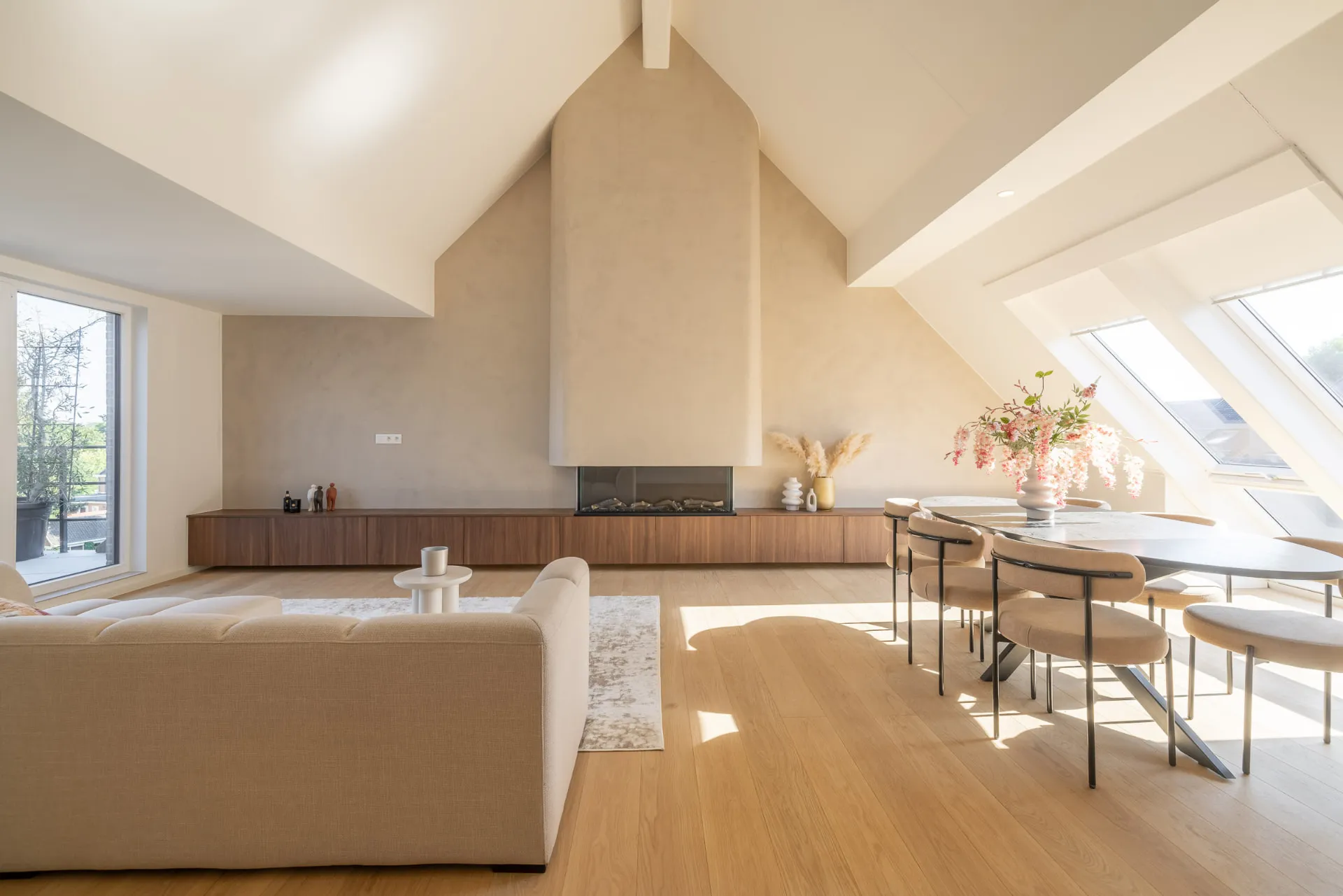 Penthouse Stadsomvaart, Hasselt — leefruimte onder het dakgebinte met haard en eettafel